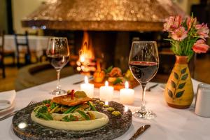 a table with a plate of food and two glasses of wine at Hotel Jose Antonio Puno in Puno