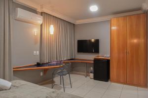 a room with a desk with a television and a bed at Honorato Hotel by Easy Hotéis in Rio Verde