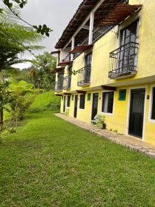 a yellow building with windows and a green yard at Hotel Villa Aventura in Cuetzalán del Progreso +8 photos