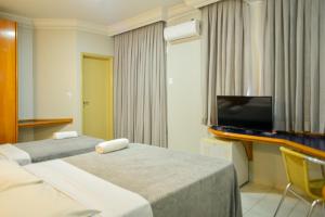 ein Hotelzimmer mit 2 Betten und einem Flachbild-TV in der Unterkunft Honorato Hotel in Rio Verde