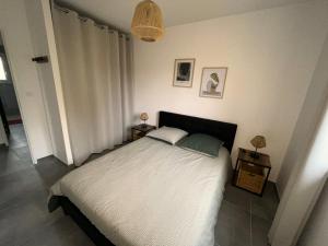een slaapkamer met een wit bed en 2 nachtkastjes bij LA VREMONTOISE in Mâcon
