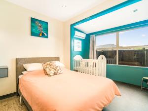 懷蒂昂格的住宿－Acacia Cote - Whitianga Holiday Home，一间卧室设有一张婴儿床和大窗户