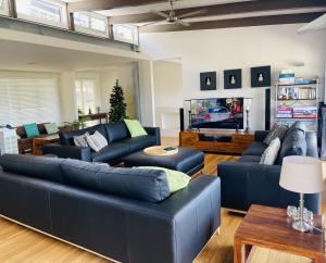 sala de estar con sofás azules y TV en Ohana Beach House, en Tangalooma