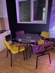 a dining table and chairs with purple and yellow chairs at Apartman Monti Vlašić in Vlasic