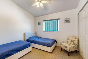 a bedroom with two beds and a chair and a window at Catch Me By The Sea in Clearwater Beach
