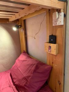 ein Bett mit einem rosa Kissen in einem kleinen Zimmer in der Unterkunft Anacrusa Hostel in Epuyén