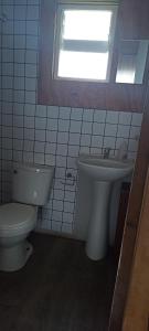 a bathroom with a toilet and a sink and a window at Cabañas La Cascada in Chaitén