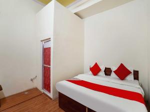 a bedroom with a bed with red pillows and a window at The Golden Crown in Faridabad