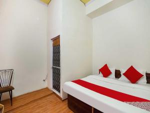 um quarto com uma cama com almofadas vermelhas e uma cadeira em The Golden Crown em Faridabad