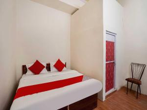 a bedroom with a bed with red pillows and a window at The Golden Crown in Faridabad