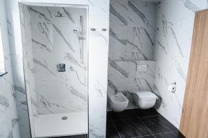 a white bathroom with a toilet and a shower at Hotel Flora in Schwäbisch Gmünd