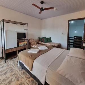 a bedroom with a bed with a fan and a couch at Pousada dos Quiosques in Viamão