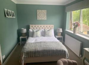 a blue bedroom with a bed and two windows at The Annexe at Greendyke House in Addingham
