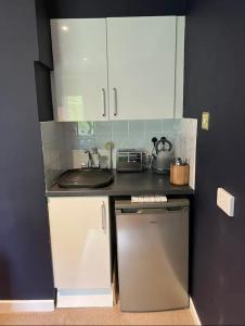 a small kitchen with white cabinets and a sink at The Annexe at Greendyke House in Addingham