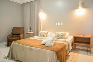 a hotel room with two beds and a chair at Honorato Hotel by Easy Hotéis in Rio Verde +40 photos