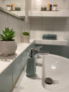 a bathroom sink with a soap dispenser on it at City Apartment in Piešťany +21 photos