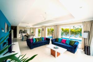 a living room with blue couches and a tv at Special offer! Villa Bueno with private pool&beach in Punta Cana