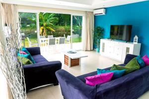 Special offer! Villa Bueno with private pool&beach في بونتا كانا: غرفة معيشة مع اثنين من الأرائك الزرقاء وتلفزيون