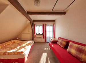 een slaapkamer met 2 bedden en een rode bank bij Apartmány Hamříkova stáj in Dolní Moravice