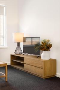 a living room with a tv on a wooden entertainment center at MAC South Yarra by Melbourne Apartment Collection in Melbourne