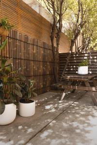 un banco de madera sentado junto a una valla con macetas en MAC South Yarra by Melbourne Apartment Collection, en Melbourne
