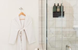 a white robe hanging on a shower door in a bathroom at Talavera Palm Springs in Palm Springs