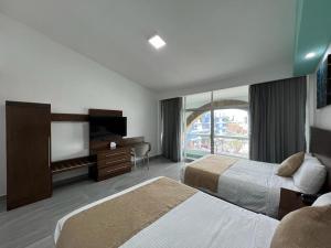 a hotel room with two beds and a flat screen tv at Solamar Inn Mazatlan in Mazatlán
