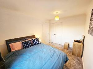 a bedroom with a blue bed with pillows on it at Whitefield, Manchester in Manchester