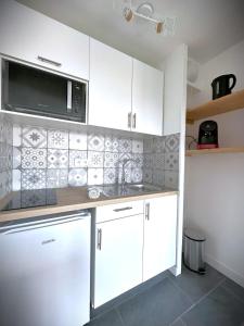 a kitchen with white cabinets and a microwave at Le Sunset-Cosy appart avec parking et balcon in Le Havre