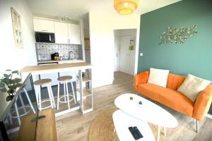 a living room with an orange couch and a kitchen at Le Sunset-Cosy appart avec parking et balcon in Le Havre