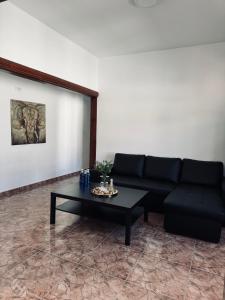Sala de estar con sofá negro y mesa de centro en Avenida 52 A en Los Llanos de Aridane