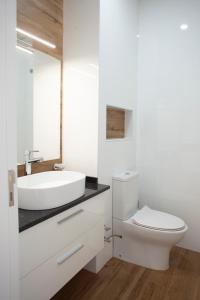 La salle de bains est pourvue d'un lavabo blanc et de toilettes. dans l'établissement 3 bdr aprt, rooftop pool & seaview - LCGR, à Praia