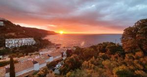 an aerial view of a city with the sun setting over the water at ⭑ Sea views + private beach. What else? ⭑ in Tossa de Mar