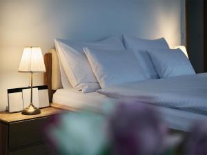 IMPERIAL Apartments في كارلوفي فاري: سرير مع وسائد زرقاء ومصباح على طاولة