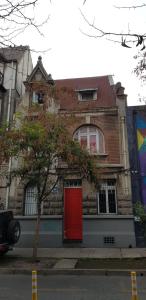 a brick house with a red door on a street at Wild Bellavista Hostel in Santiago