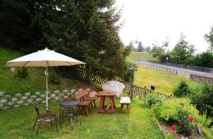 a table and chairs with an umbrella in a garden at Garni Panoramik in Ortisei