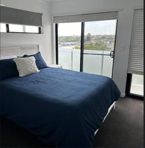 sypialnia z niebieskim łóżkiem i dużym oknem w obiekcie New Farm 2 Bed 2 Bath 1 Car space perfect location w mieście Brisbane