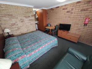 a hotel room with a bed and a tv at Dragon Phoenix Resort in Moree