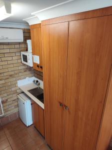 una pequeña cocina con armarios de madera y fregadero en Dragon Phoenix Resort, en Moree