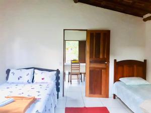 une chambre avec deux lits et une porte avec une table dans l'établissement Casa da Jane, à Parati