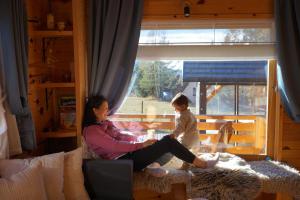 a woman and a child sitting in a room with a window at Zlatiborska sekvoja in Zlatibor