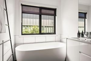 une salle de bain blanche avec une baignoire et une fenêtre dans l'établissement 2 Minutes By Bike - On the Rail Trail, à Bright 18 autres photos