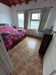 1 dormitorio con 1 cama, 2 ventanas y suelo de baldosa en Casa del Valle en Ushuaia