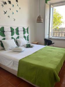 a bedroom with a large bed with a green blanket on it at Peniche Hostel in Peniche