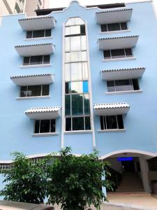 un edificio azul con un árbol delante de él en HOTEL BLUE COSTA Panama en Panamá