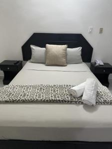 ein Bett mit einer schwarzen und weißen Bettdecke und Kissen in der Unterkunft HOTEL BLUE COSTA Panama in Panama-Stadt