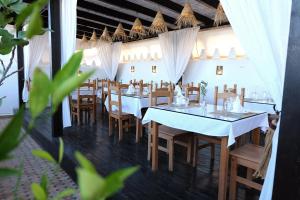 una sala da pranzo con tavoli bianchi e sedie in legno di Riad Alassala Fes a Fes