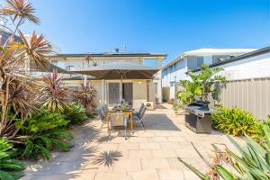 安娜湾Bel Air, 8A Ocean Ave - pet friendly, water views and air con的庭院配有遮阳伞和桌椅。