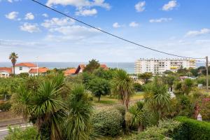 比亞里茨的住宿－Cosy duplex apartment with ocean view in Biarritz - Welkeys，享有棕榈树和建筑的城市美景