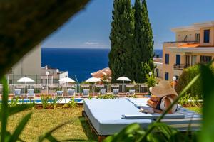 a woman in a hat sitting on a chaise lounge at a resort at Estrelicia Hotel in Funchal